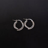 Orecchini a cerchio in oro bianco con swarovski bianchi dentro e fuori su sfondo nero