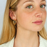 Orecchini a cerchio a trecchia in oro giallo indossati da una ragazza bionda