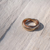 Tre anelli in uno di tre colori rosa, bianco e oro su sfondo di legno 